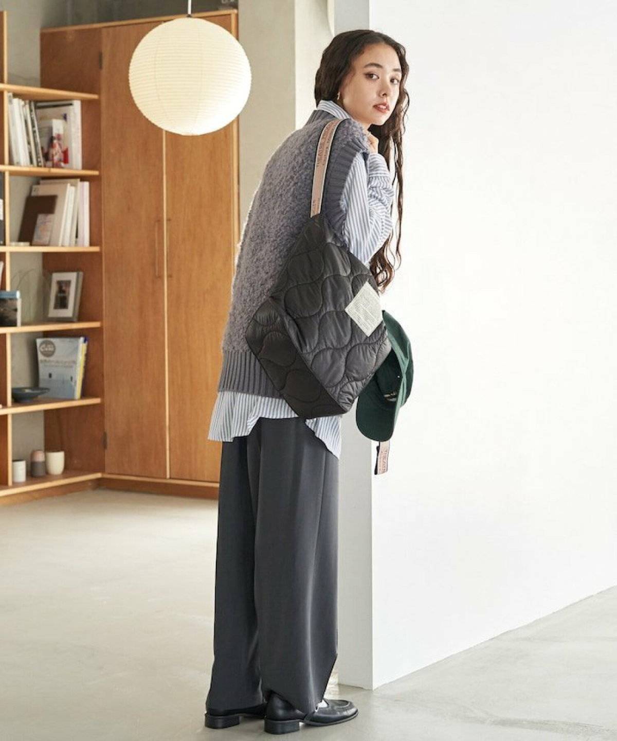 シャツにグレーのベストを重ねてグレーのパンツを穿いた女性