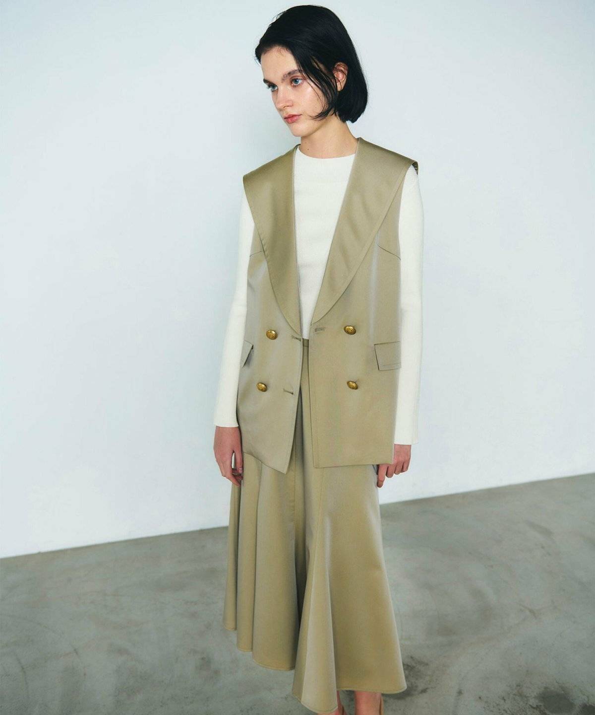 白ニットにベージュのセットアップを合わせた女性