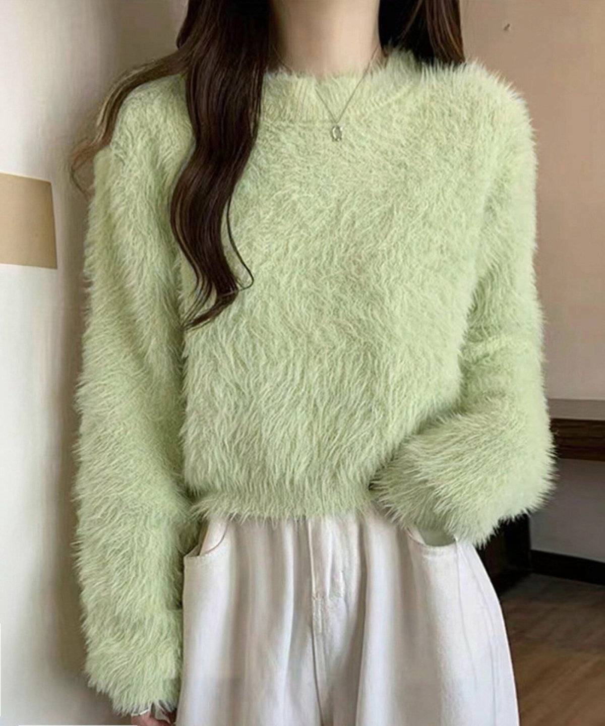 グリーンのニットに白パンツを合わせた女性