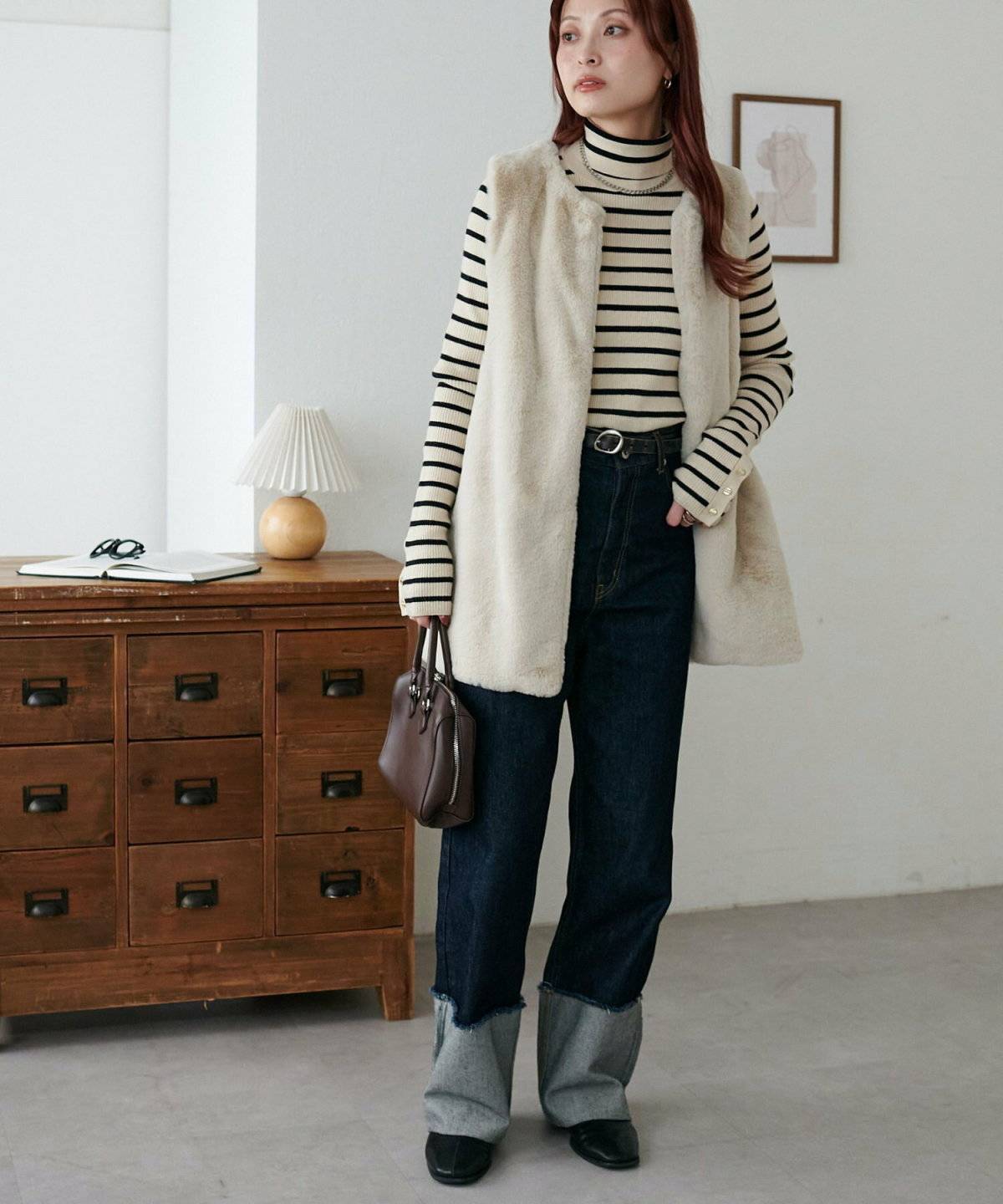 ボーダー柄トップスにファーベストを羽織ってパンツを合わせた女性
