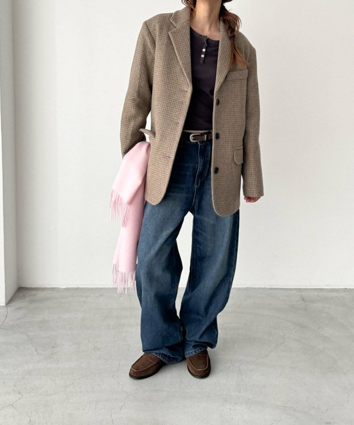 ブラウンのチェック柄ジャケットにデニムを合わせた女性