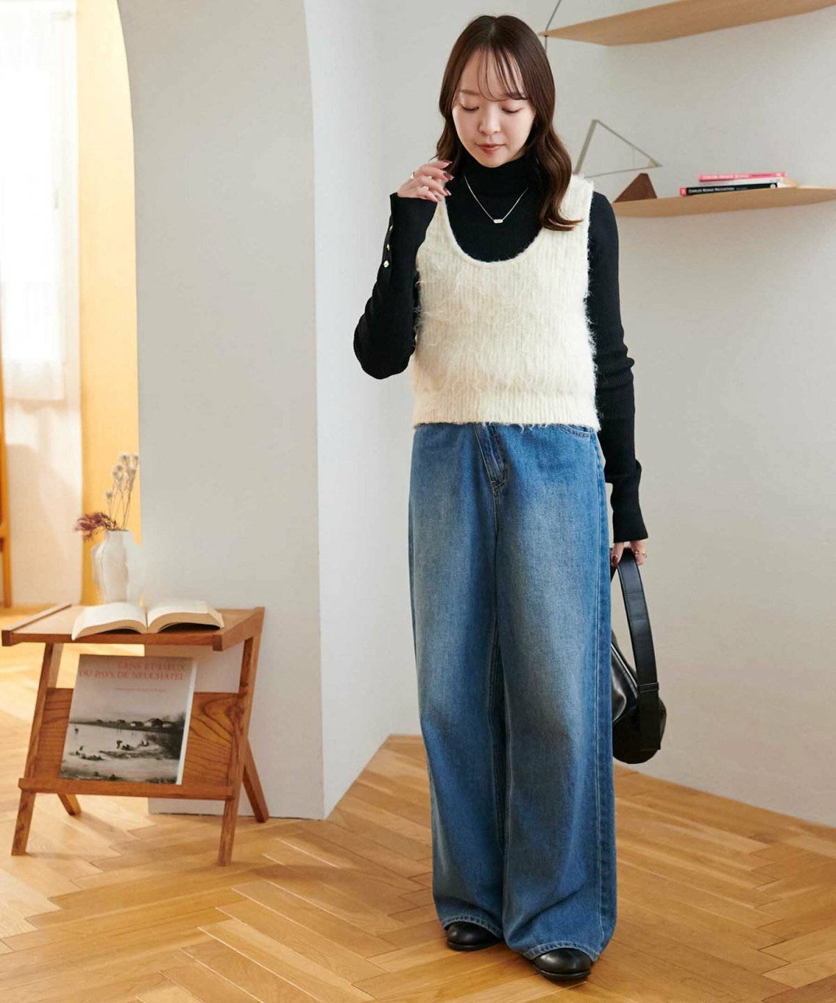 ハイネックトップスにベストを重ねてデニムを合わせた女性