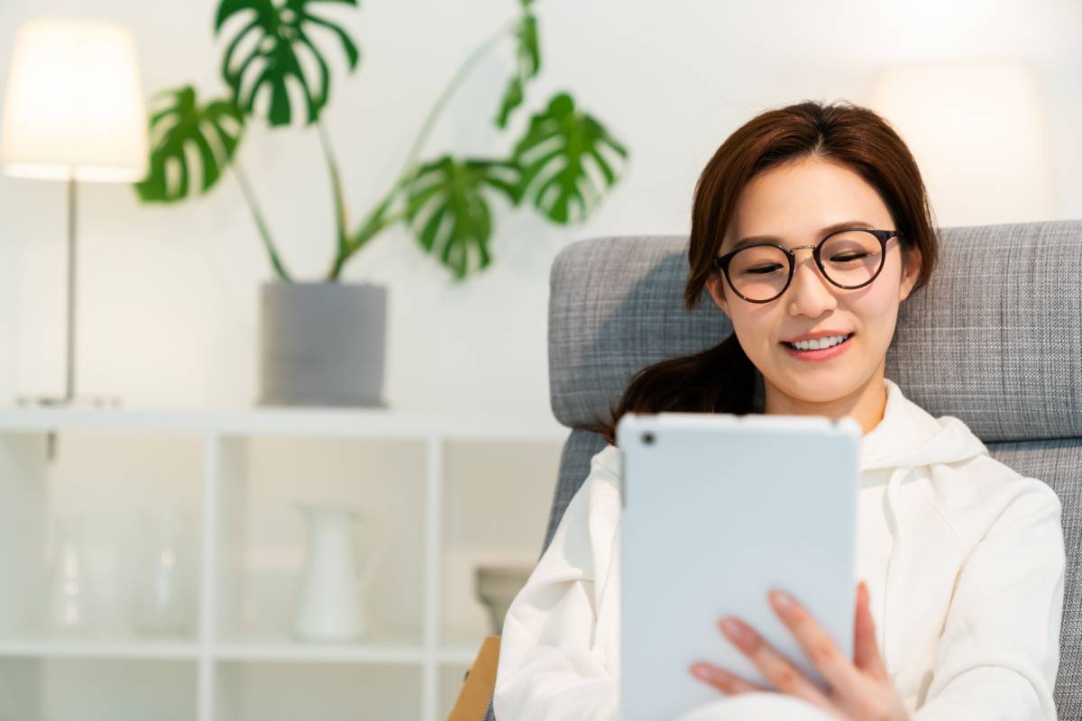部屋でタブレットを見る女性