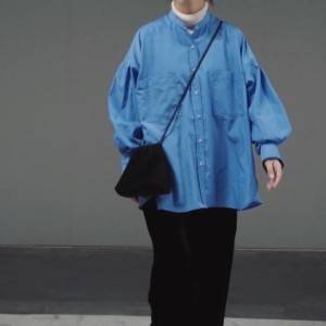  ブルーのシャツに黒パンツを合わせた女性 