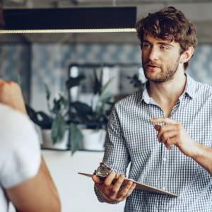  バインダーを持って同僚と話し合う男性 