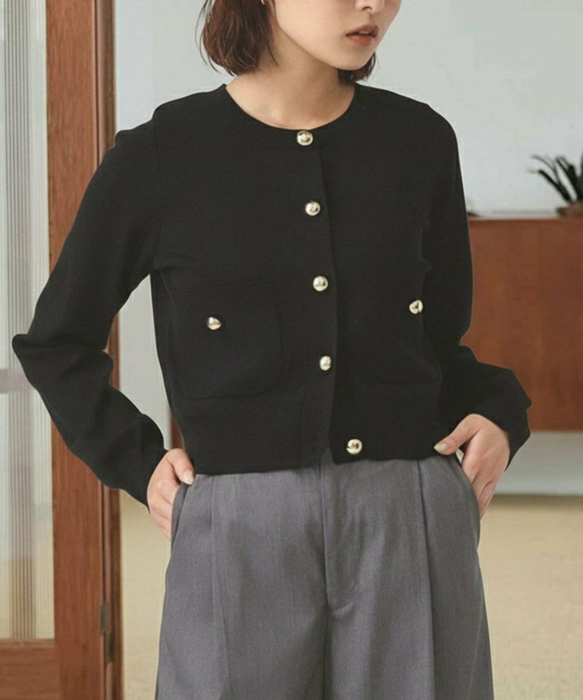 黒カーディガンにグレーのパンツを合わせた女性