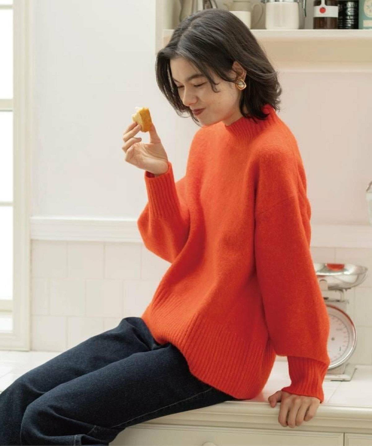 オレンジのニットにデニムを合わせた女性