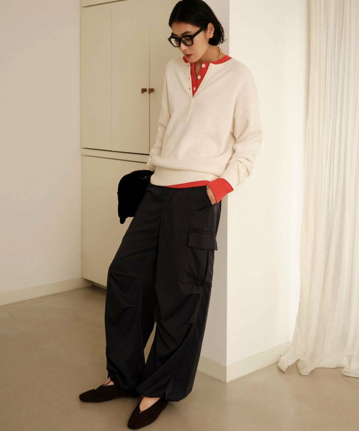 ブラウンのニットに白のカーゴパンツを合わせた女性
