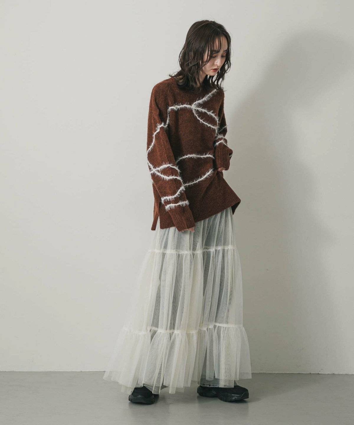 ブラウンのニットにスカートを合わせた女性
