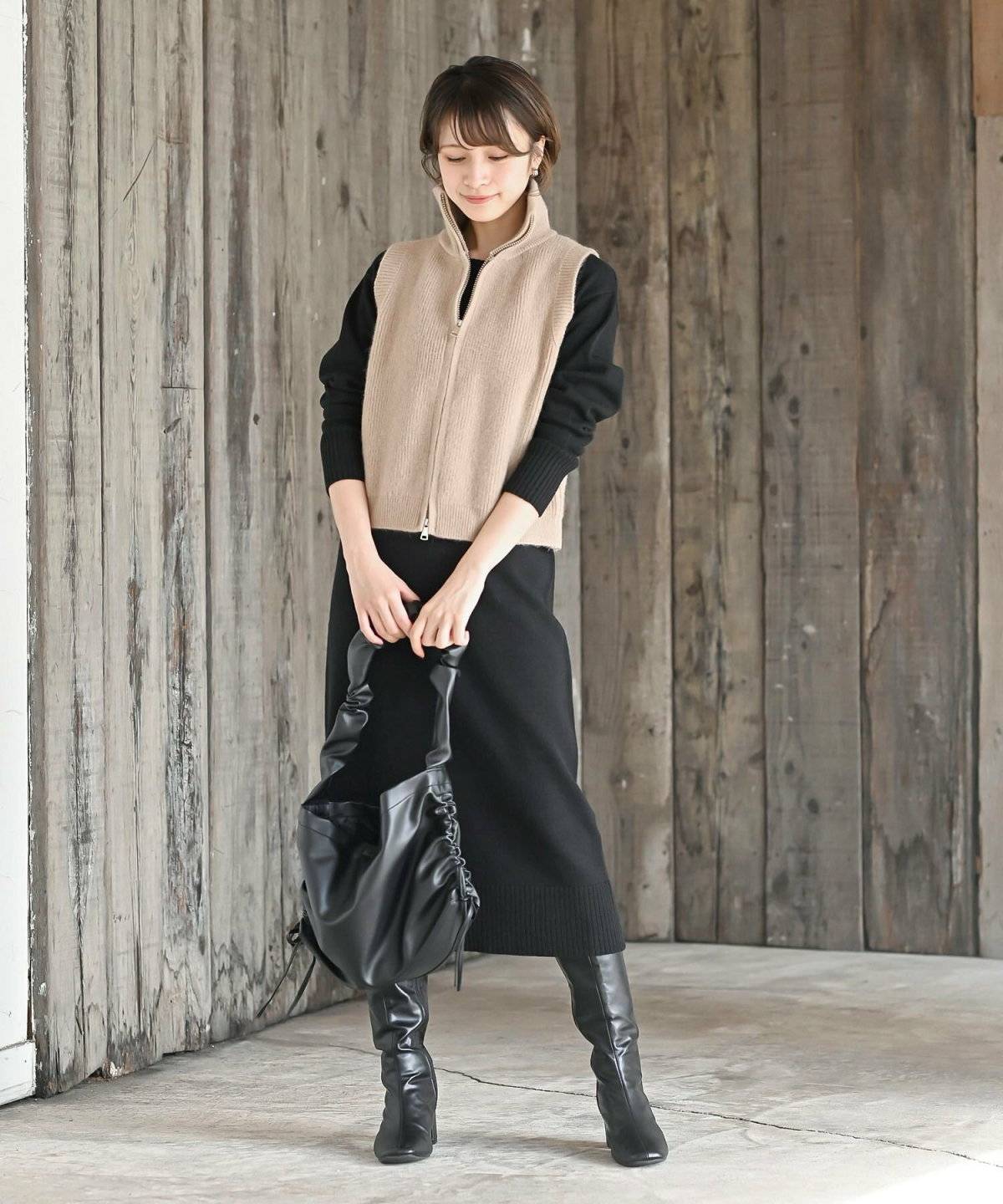 ブラックコーデにベージュのニットを合わせた女性
