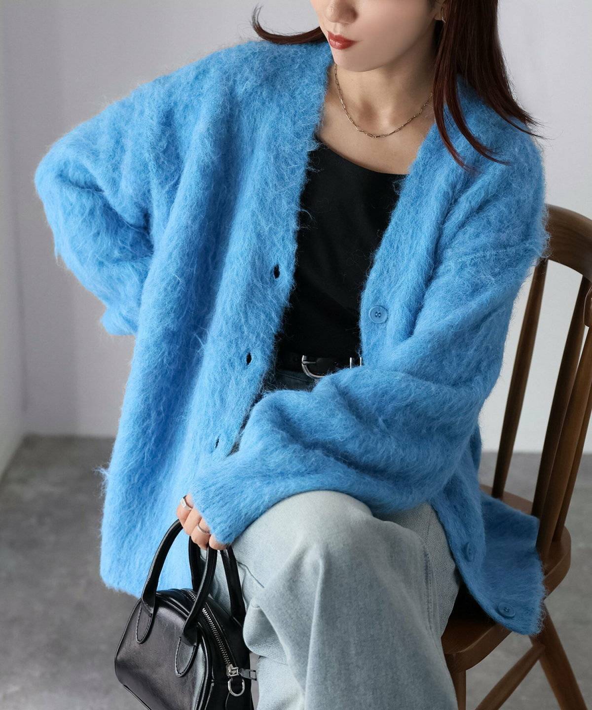 ブルーのカーディガンにデニムを合わせた女性