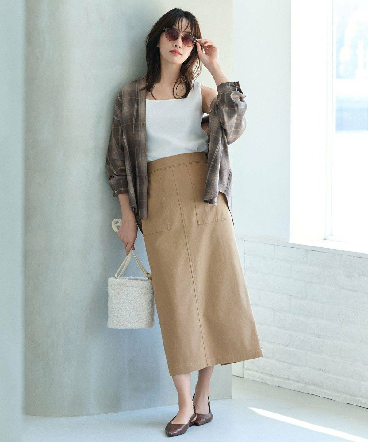 ブラウンのシャツにベージュのスカートを合わせた女性
