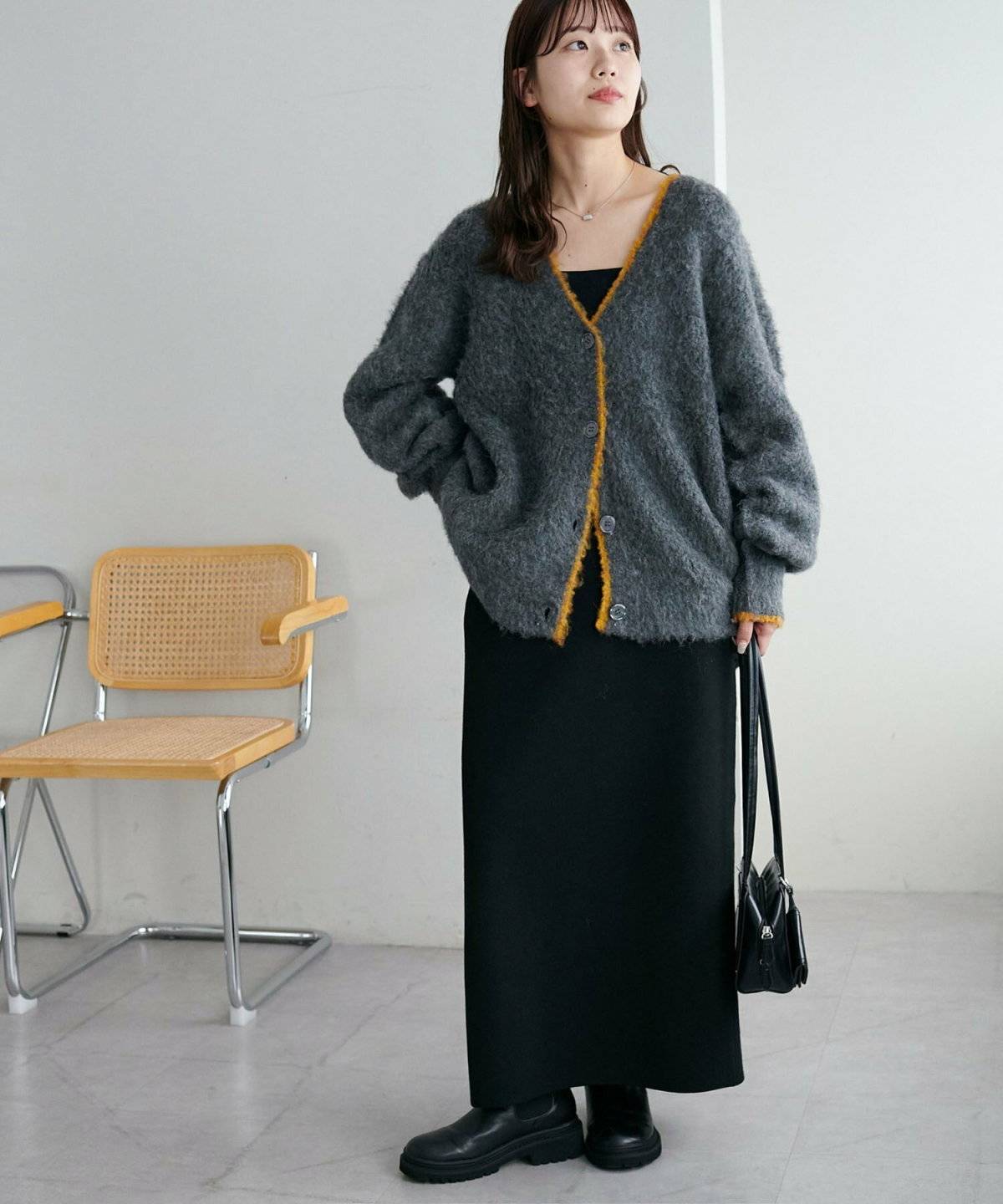 グレーカーディガンに黒スカートを合わせた女性