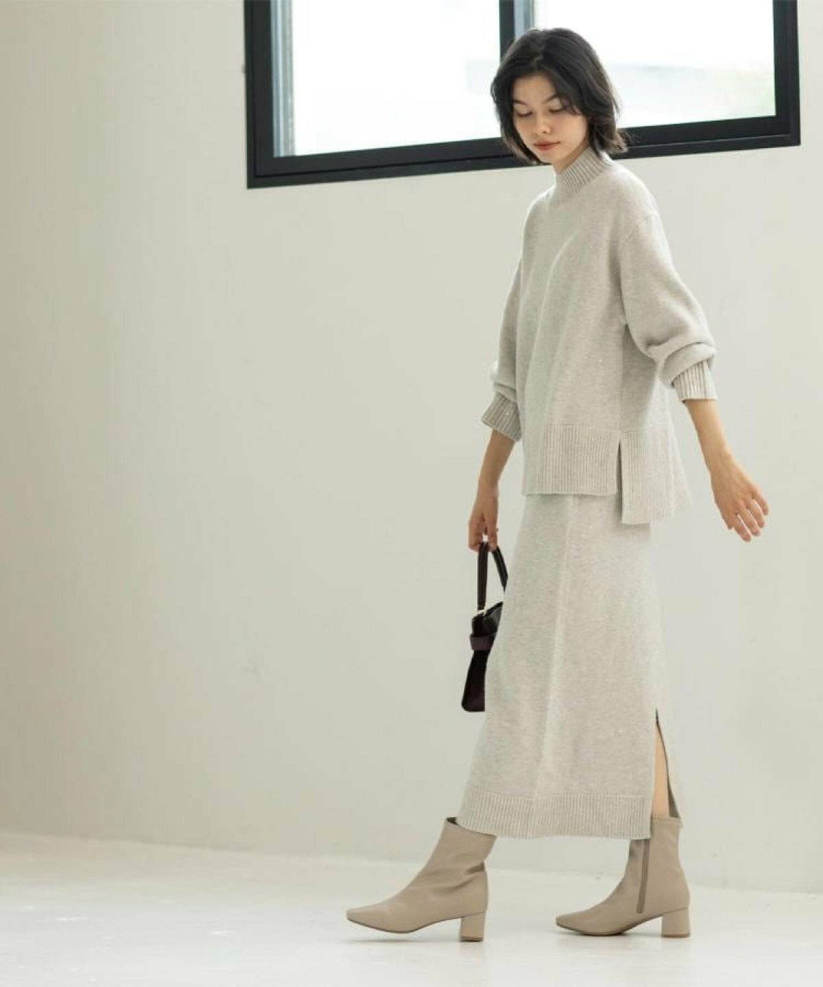 ベージュのニットセットアップを着た女性