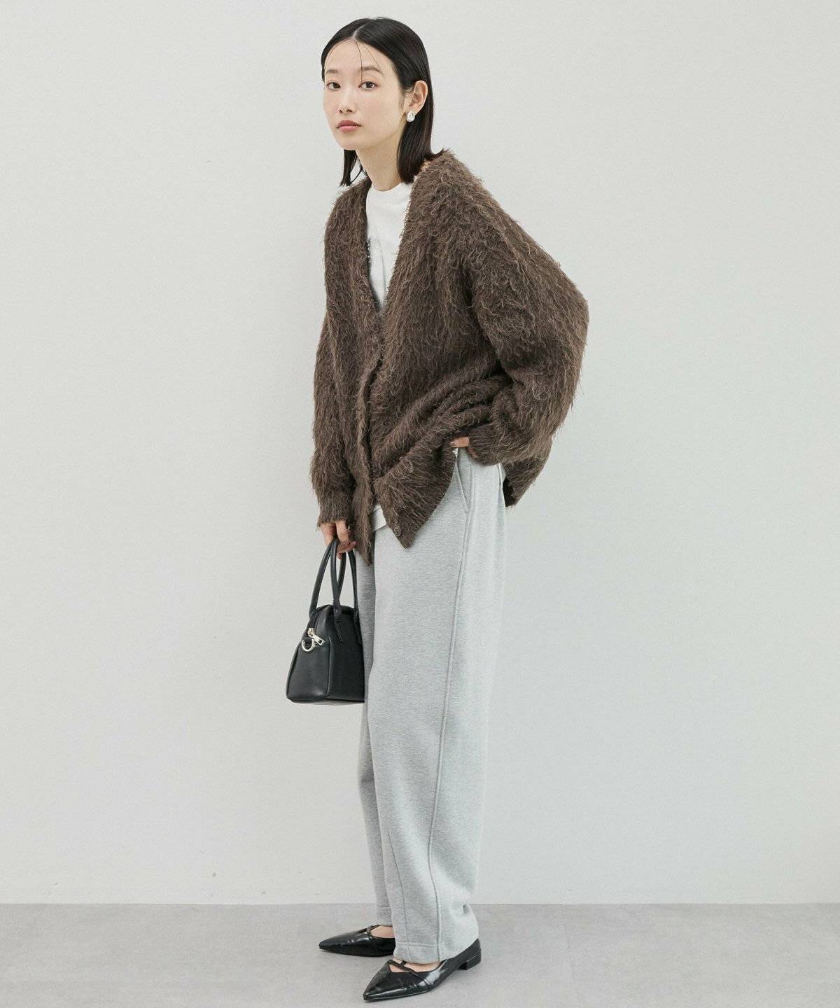 シャギーカーディガンにベージュのスウェットを合わせた女性