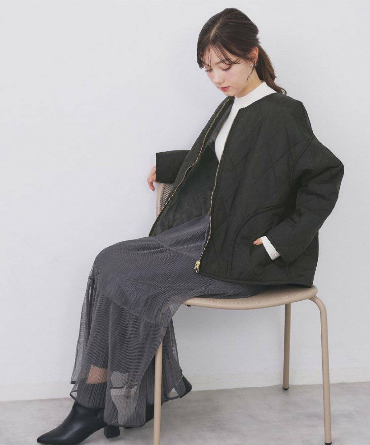 黒のブルゾンにグレーのスカートを合わせた女性