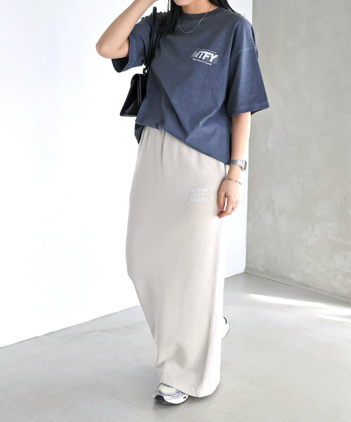 ネイビーのTシャツに白のスカートを合わせた女性