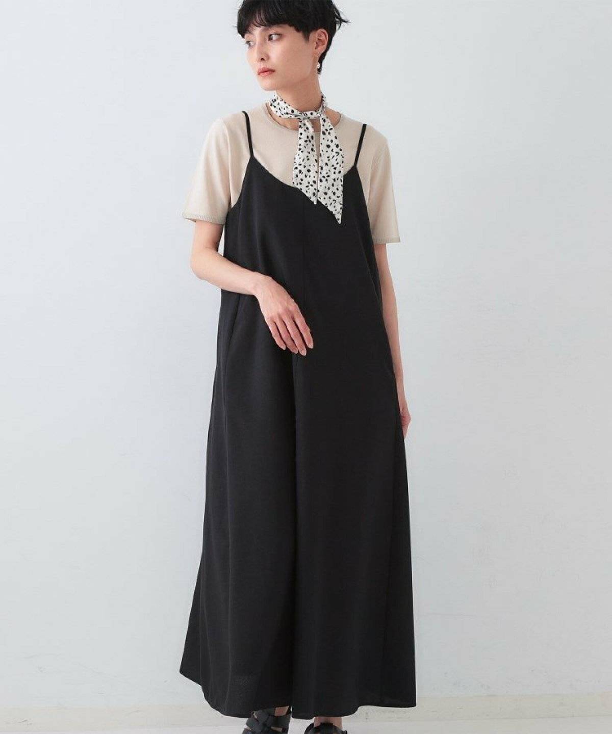 ベージュのTシャツに黒ワンピースを合わせた女性