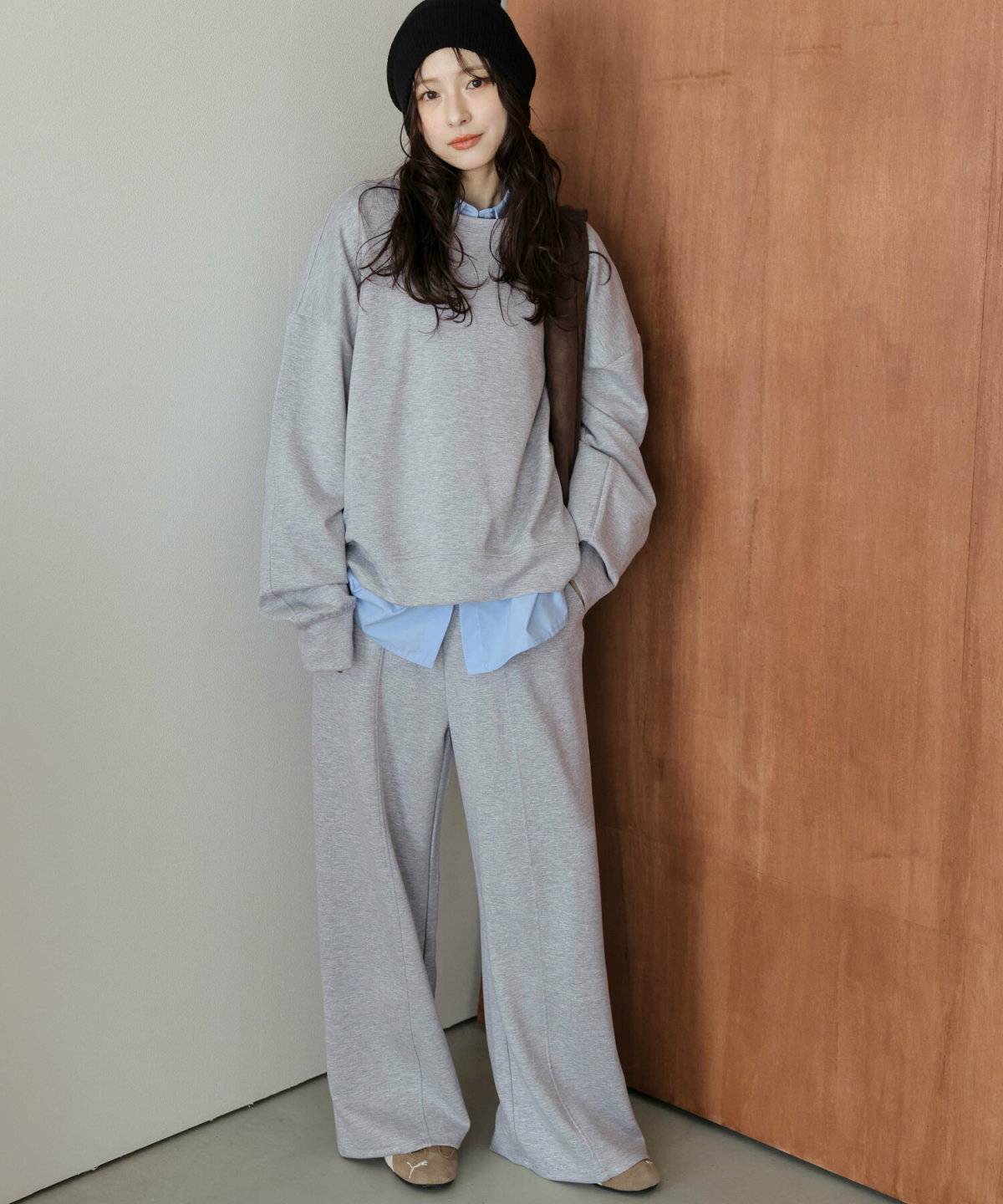 グレーのセットアップに白シャツを重ねた女性