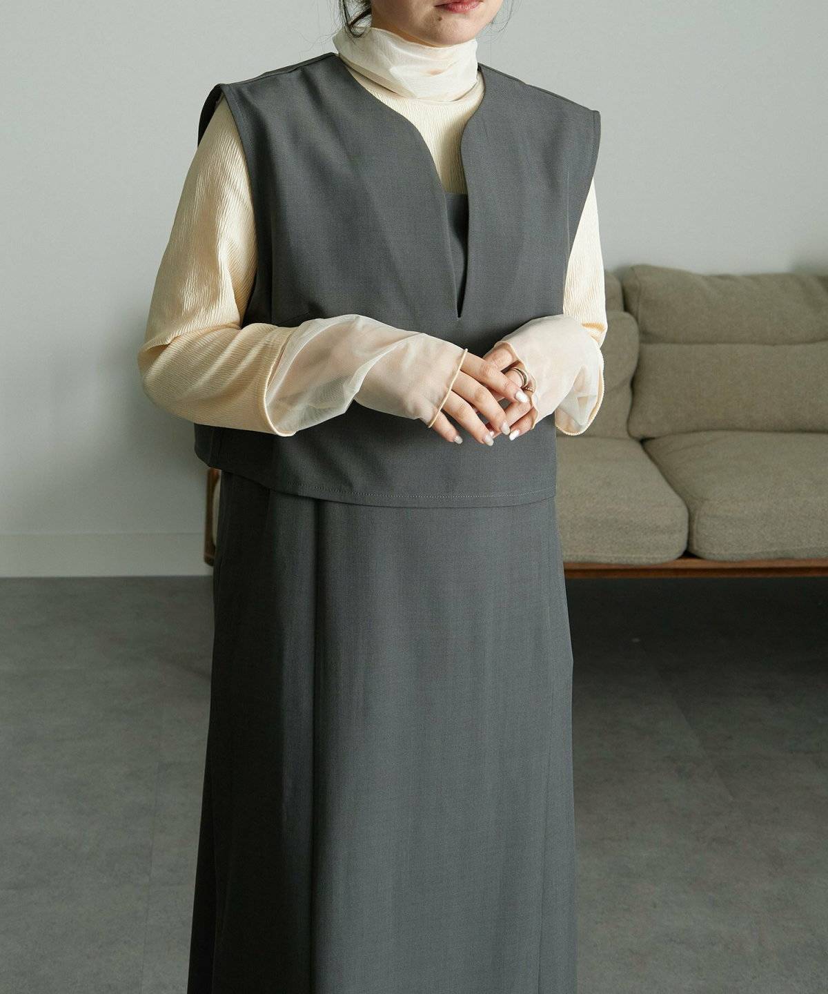 白ブラウスにグレーワンピースを重ねた女性