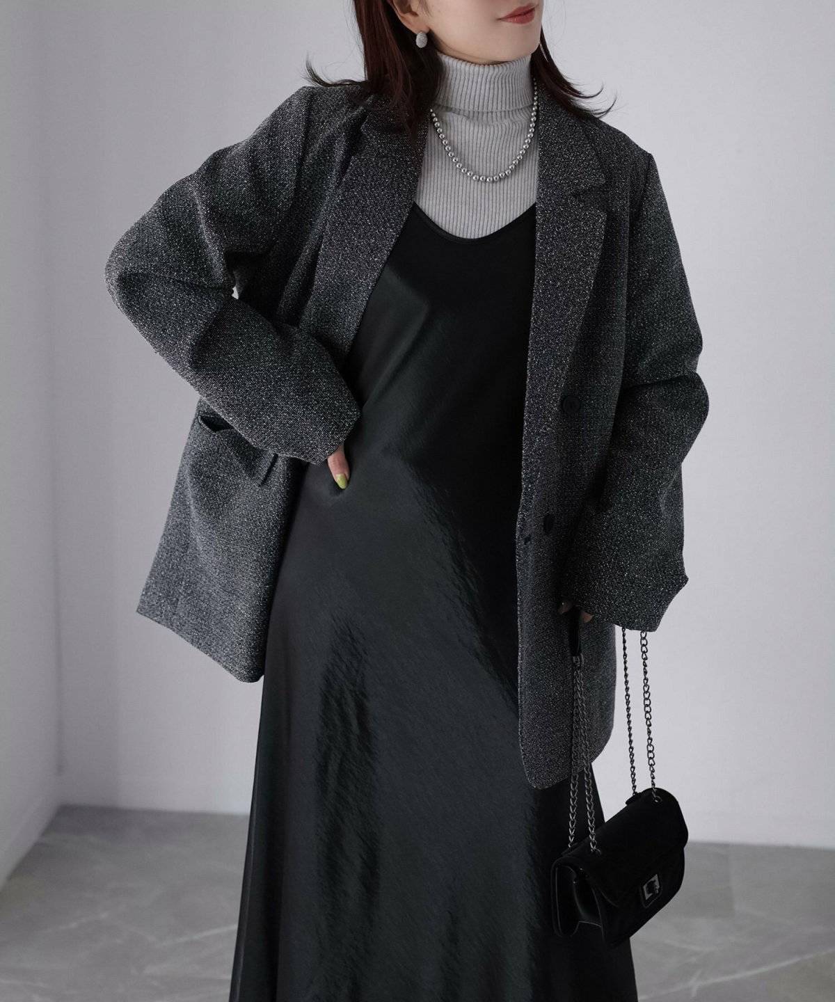 グレーのワンピースに黒ジャケットを羽織った女性