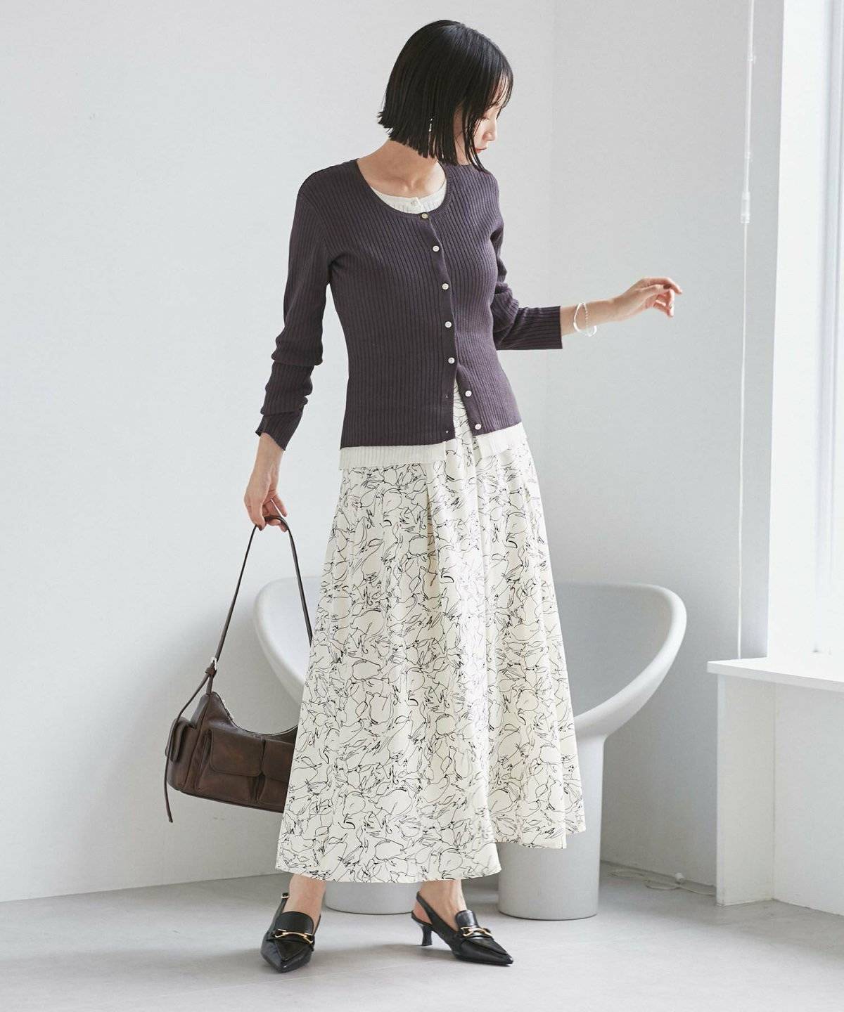 グレーのニットに花柄スカートを合わせた女性