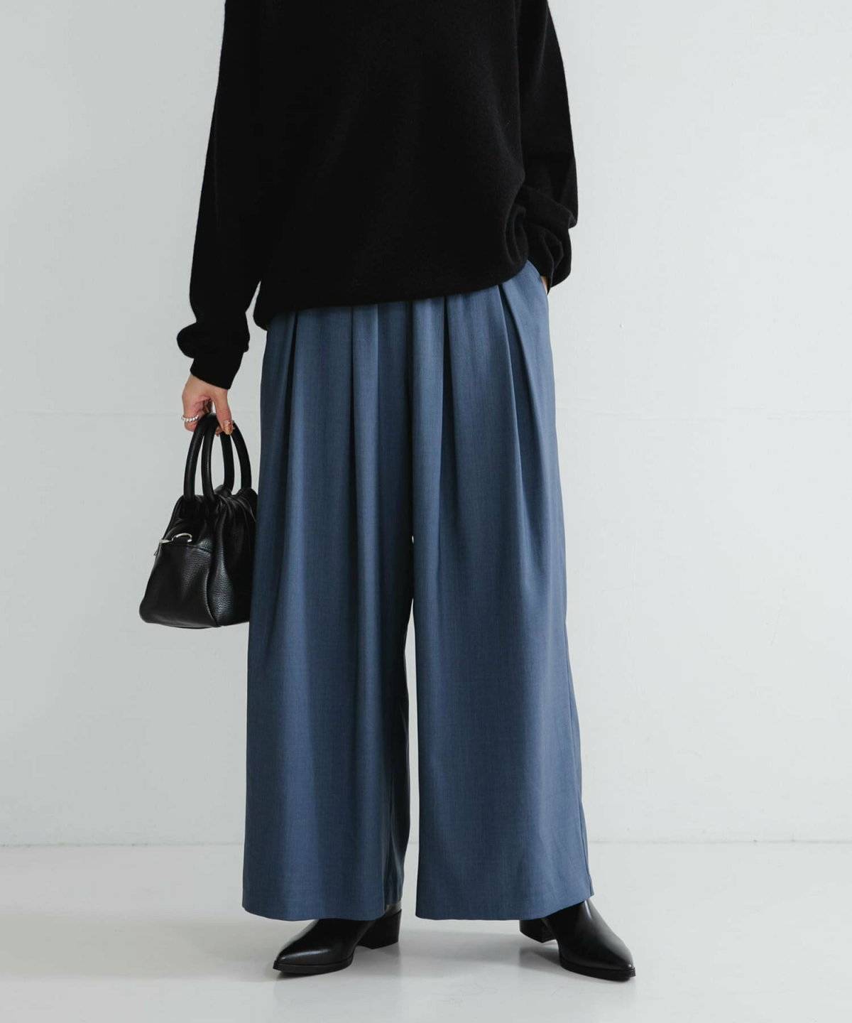 黒ニットにブルーパンツを合わせた女性