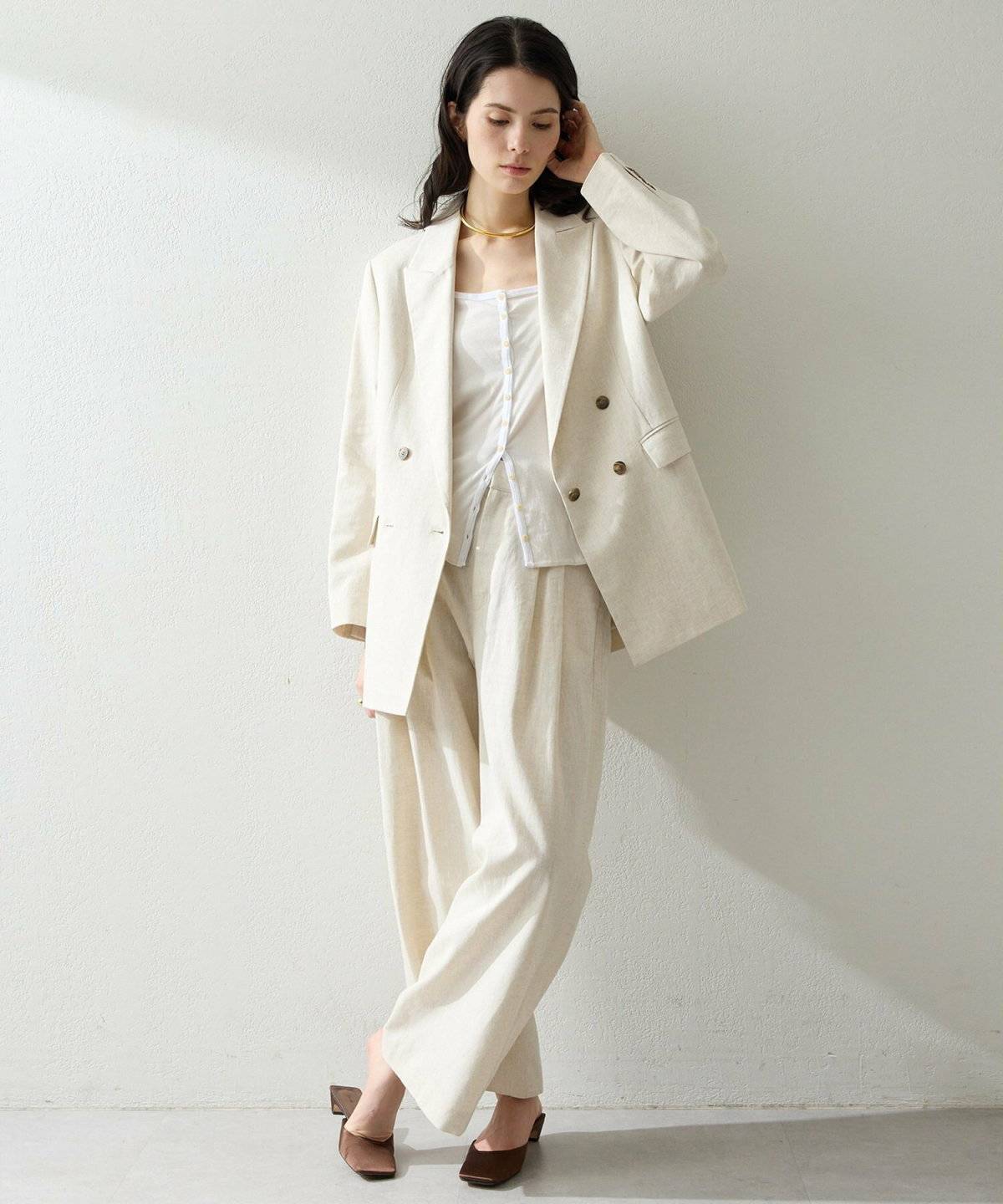 ベージュのジャケットに白のワイドパンツを合わせた女性