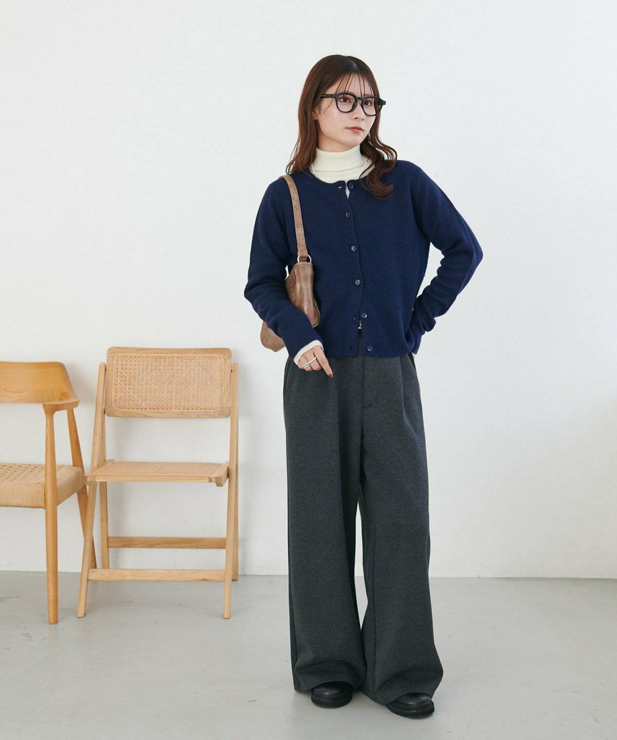 パープルのニットにグレーのパンツを合わせた女性