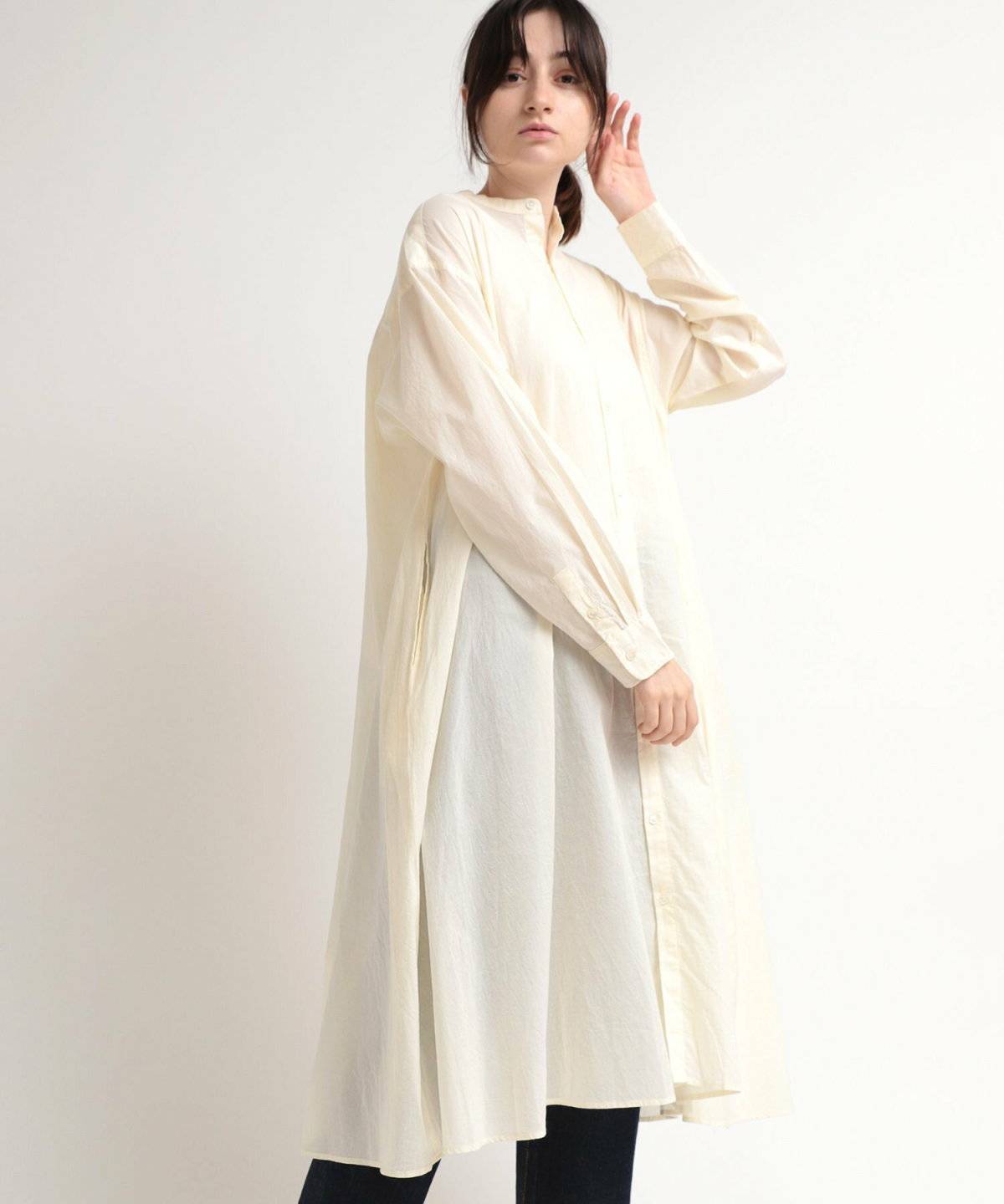 白トップスにグレーのパンツを合わせてイエローの花柄ワンピースを重ねた女性