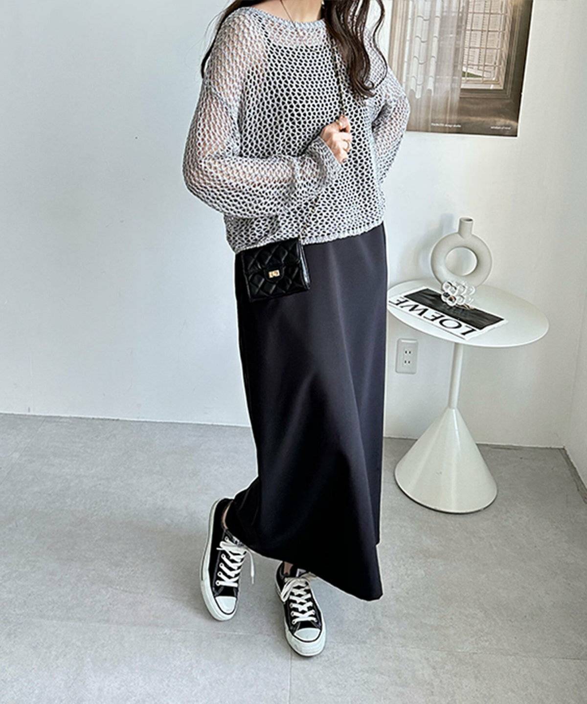 黒ワンピースにメッシュ編みニットを重ねた女性