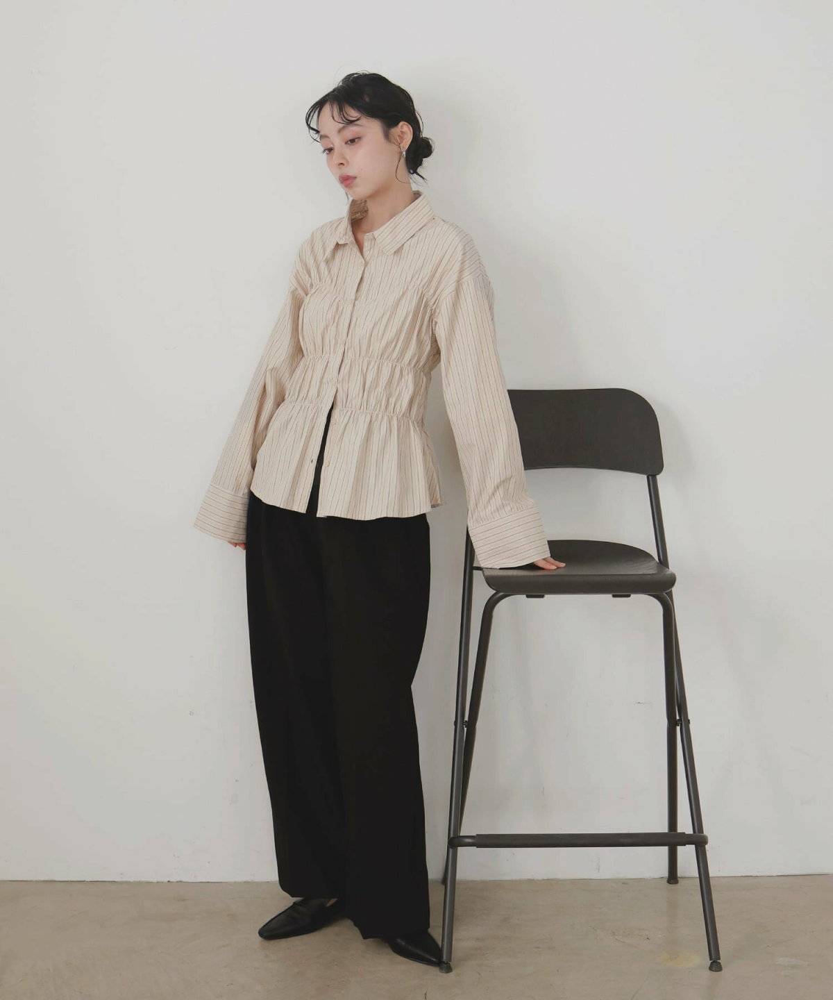 ベージュのシャツに黒パンツを合わせた女性