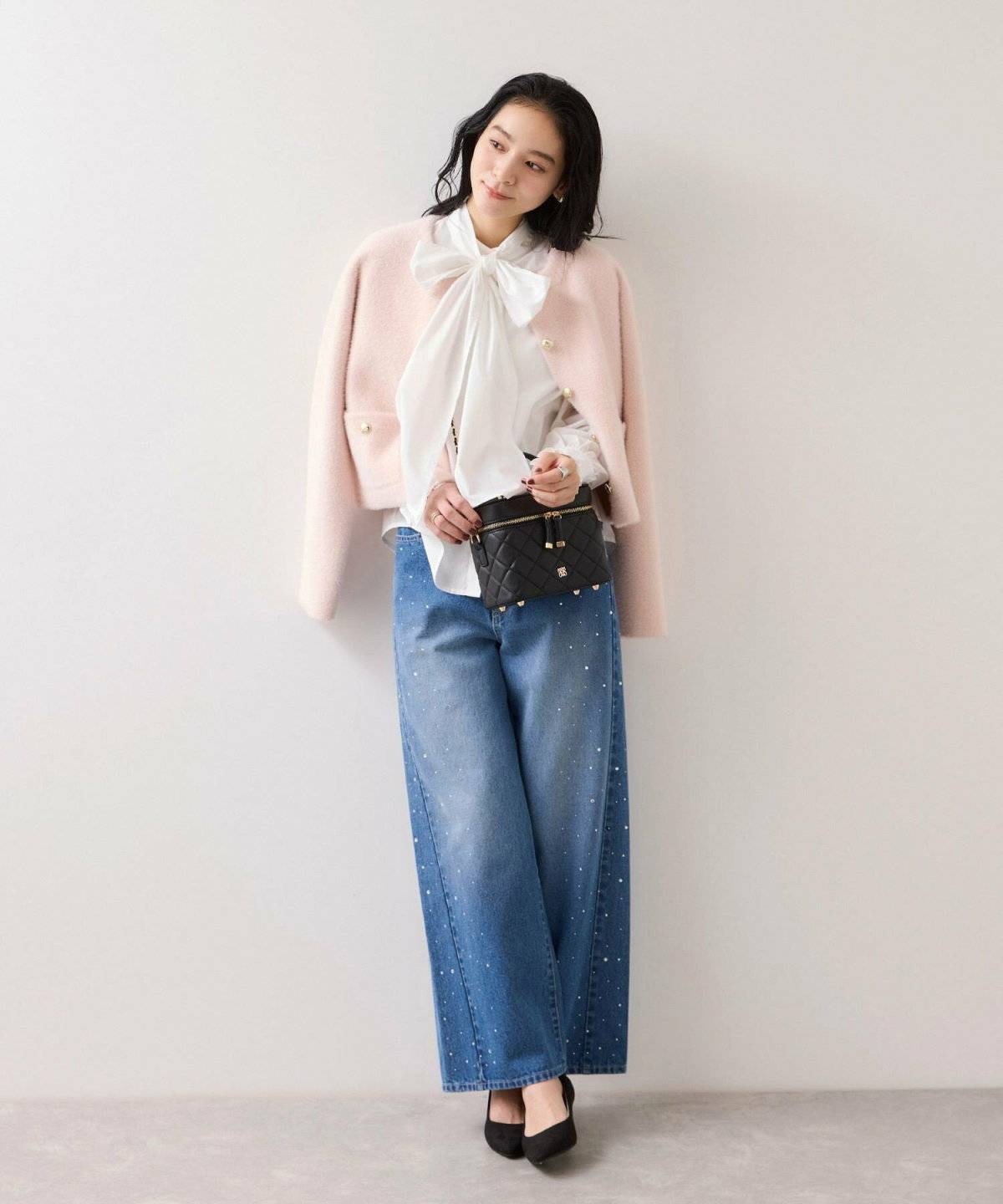 白シャツにブラウンデニムを合わせてカーディガンを肩掛けした女性