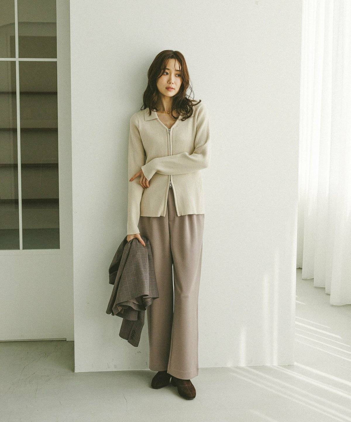 ベージュのカーディガンにパンツを合わせた女性