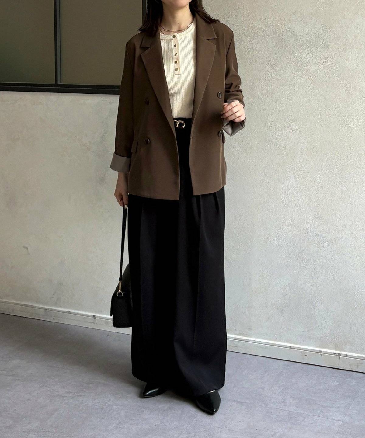 モノトーンコーデにブラウンのジャケットを羽織った女性