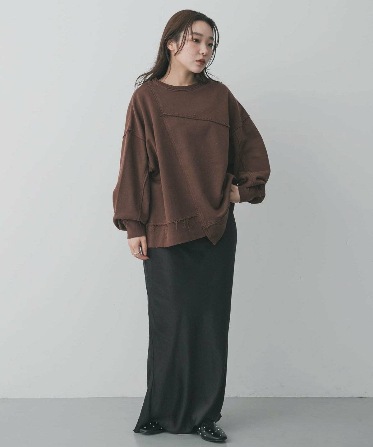 ブラウンのスウェットに黒スカートを合わせた女性