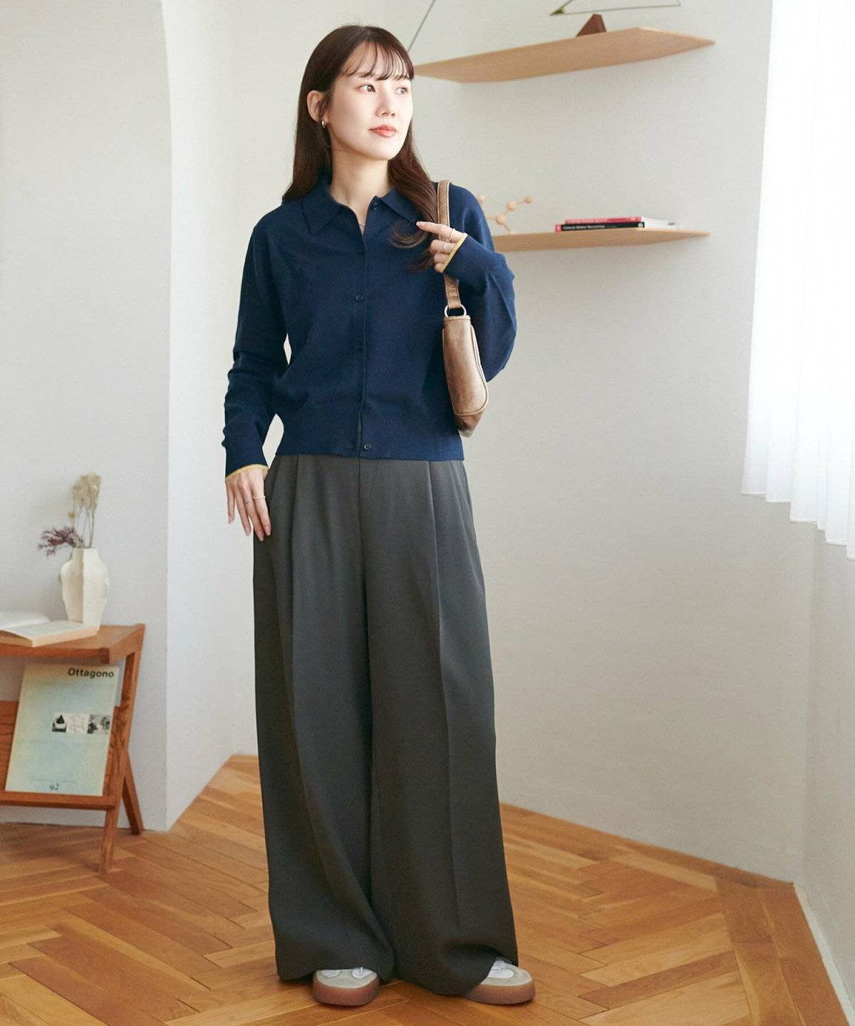 ネイビーのカーディガンにグレーのパンツを合わせた女性