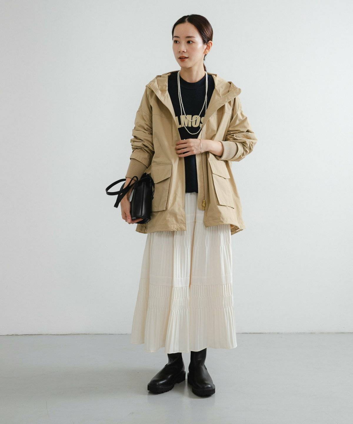 モノトーンコーデにグリーンのマウンテンパーカーを羽織った女性