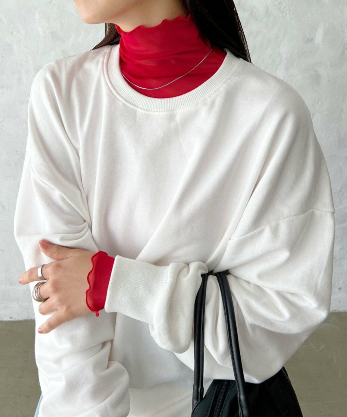 赤のハイネックトップスにグレーのスウェットを重ねてグレーのパンツを穿いた女性