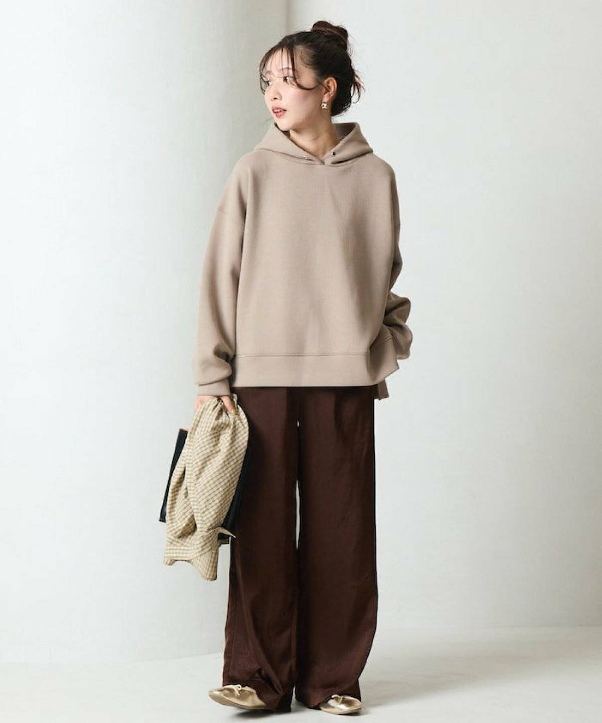 ベージュのスウェットにブラウンのパンツを合わせた女性