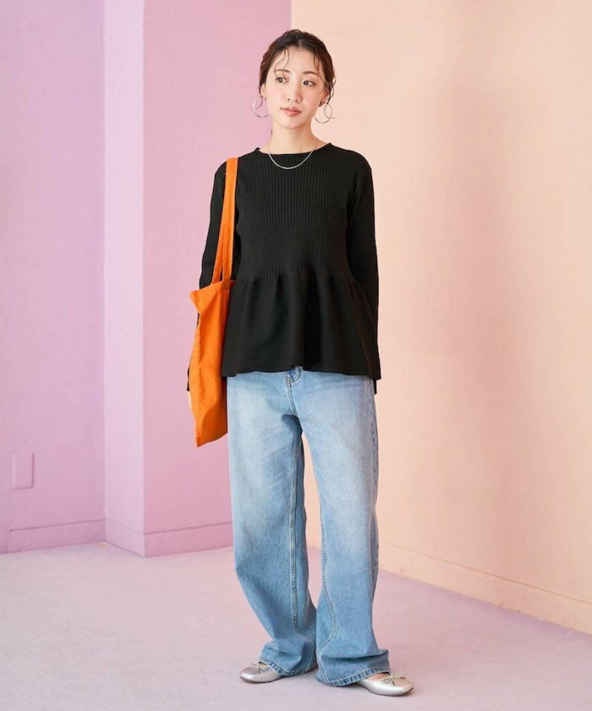 黒ニットにデニムを合わせた女性