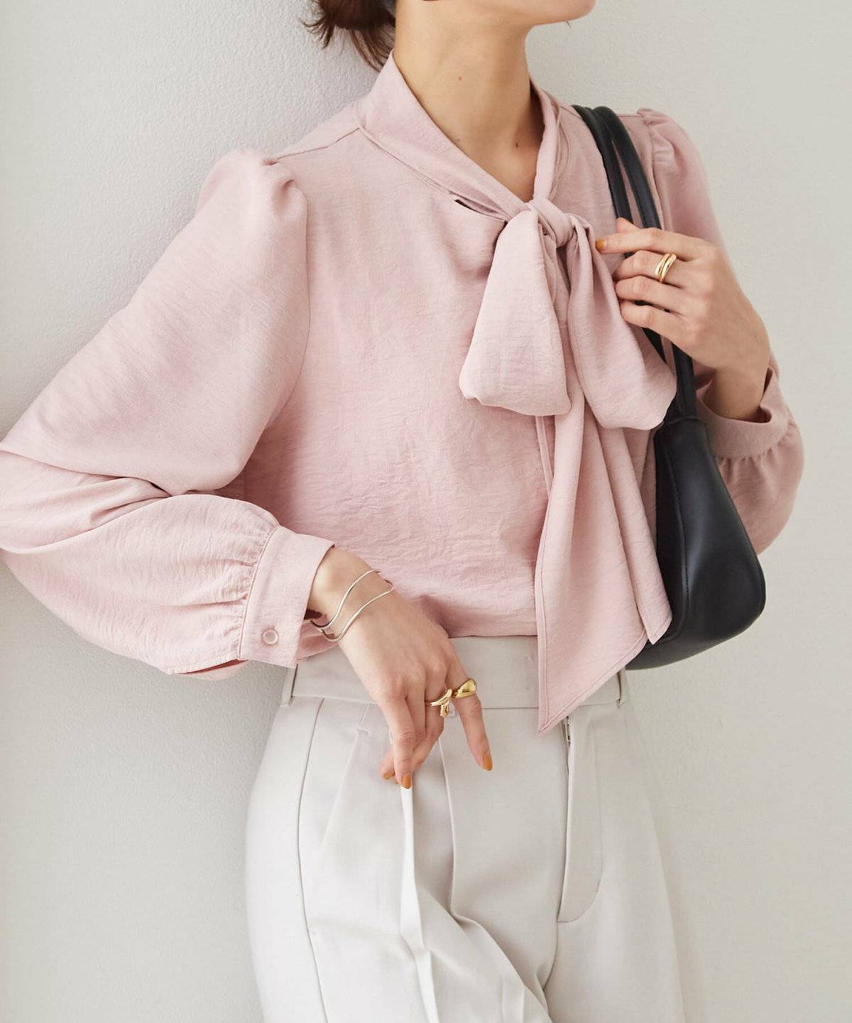 ピンクのブラウスに白パンツを合わせた女性