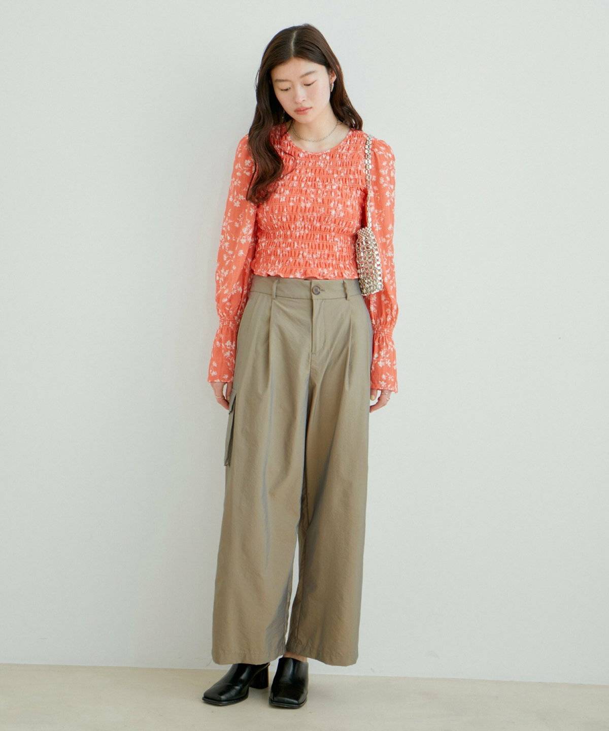 オレンジのニットにグリーンのカーゴパンツを合わせた女性