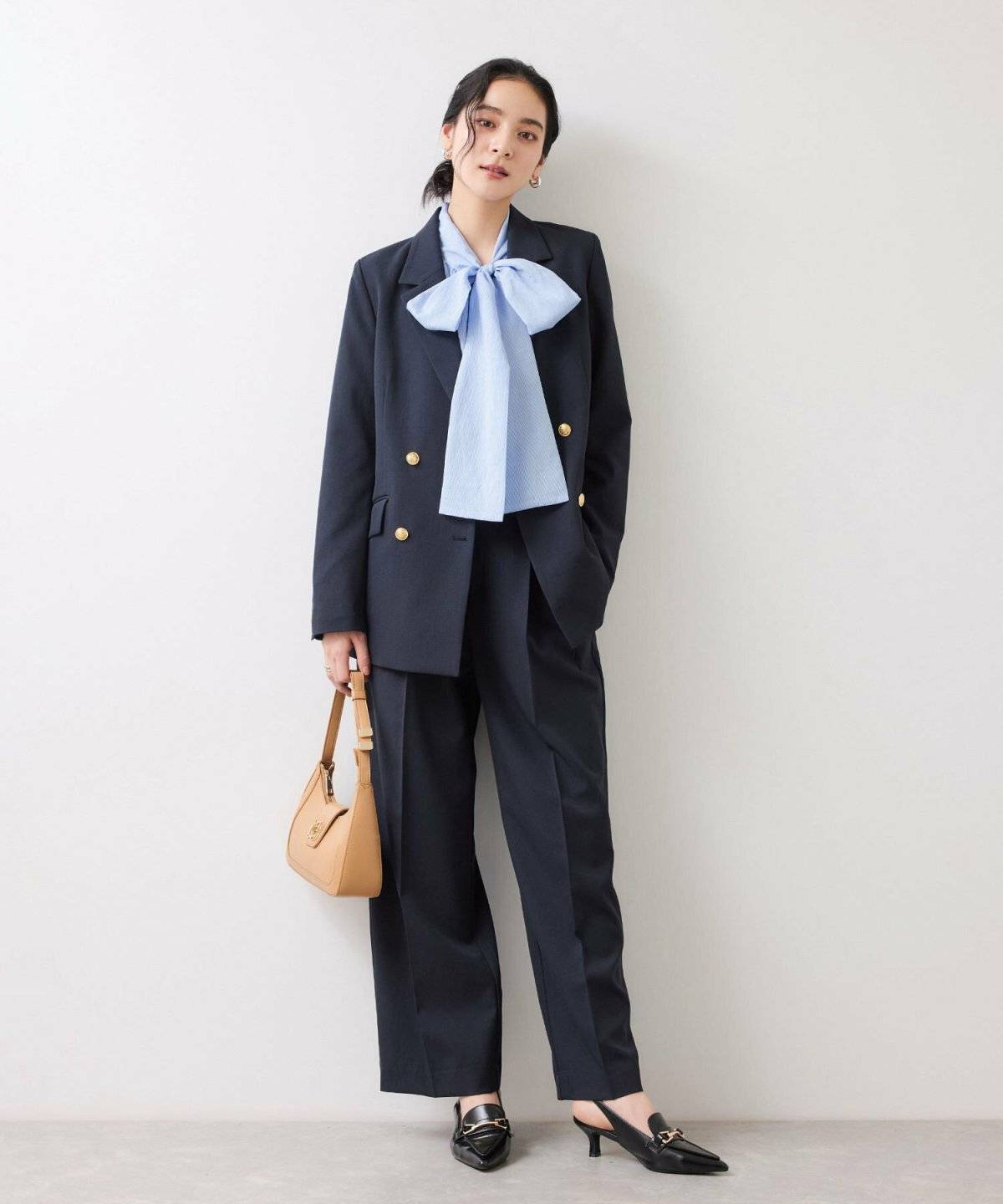 白ブラウスにネイビーのパンツを合わせてネイビーのジャケットを羽織った女性