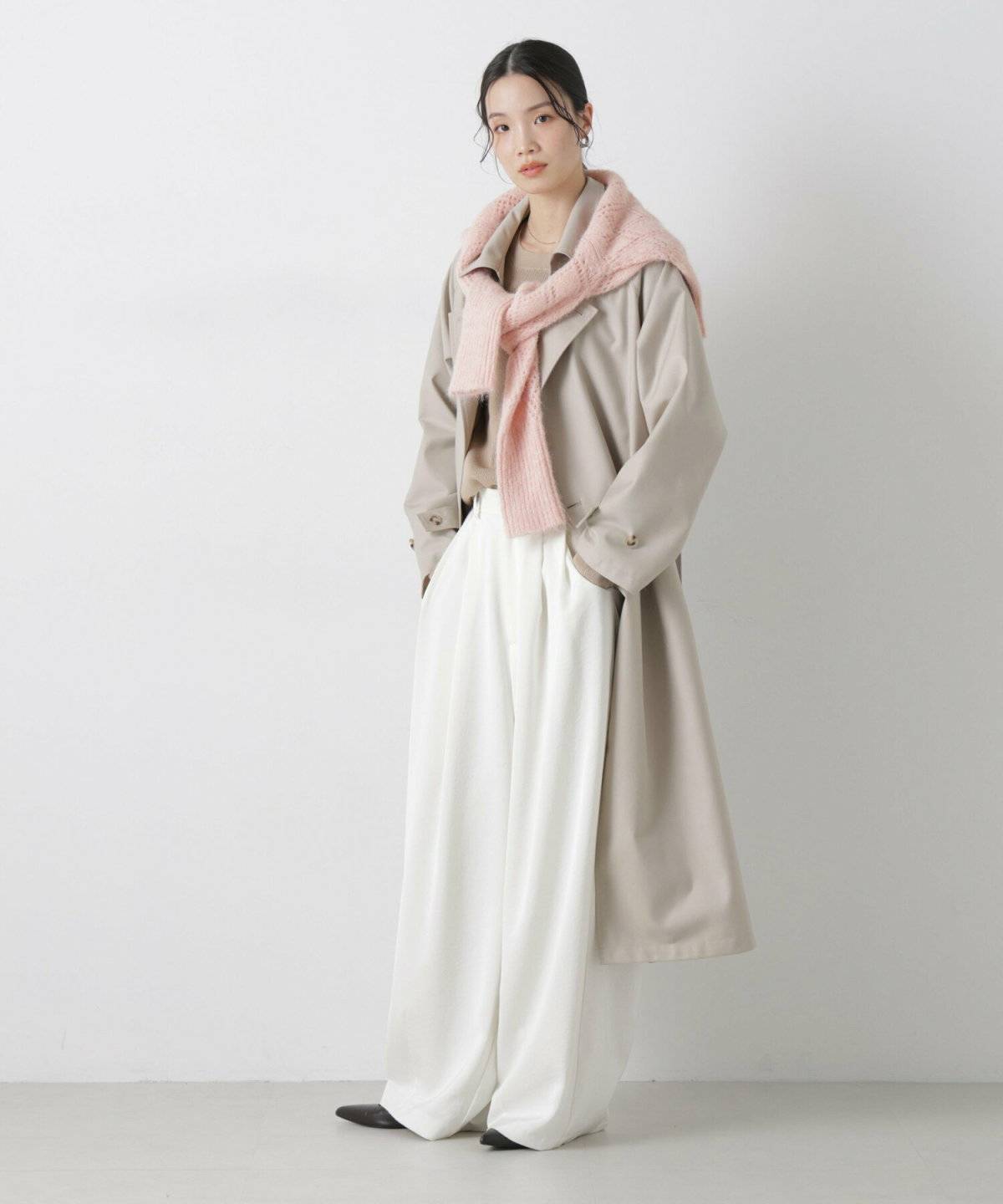 ブラウンのトレンチコートに白パンツを合わせた女性