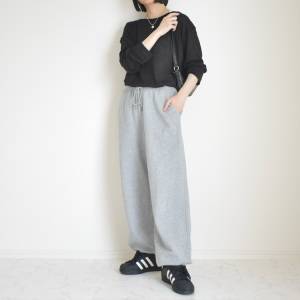  黒トップスにグレーパンツを合わせた女性 