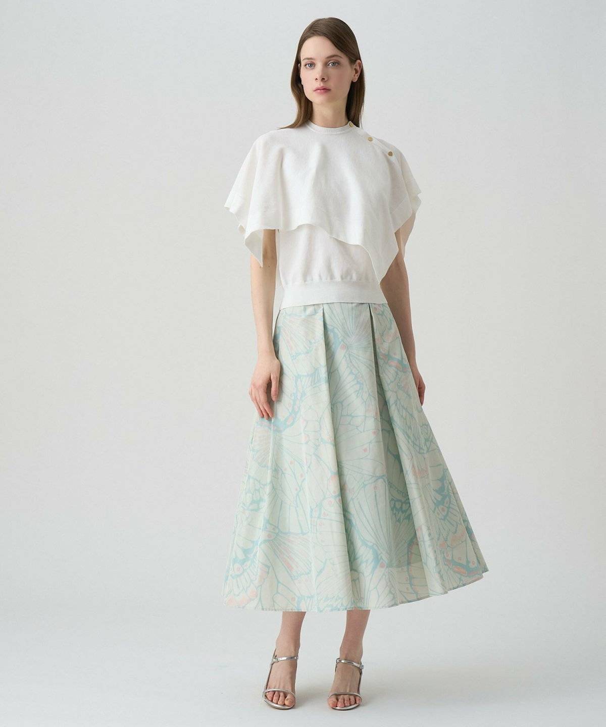 ホワイトのトップスにミントグリーンのスカートを合わせた女性