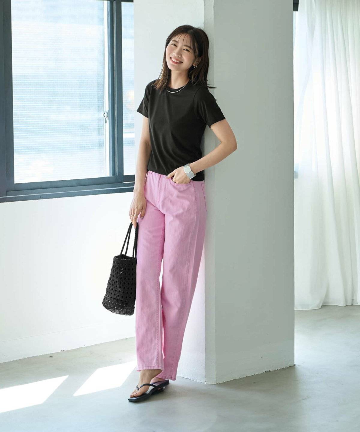 黒トップスにピンクパンツを合わせた女性