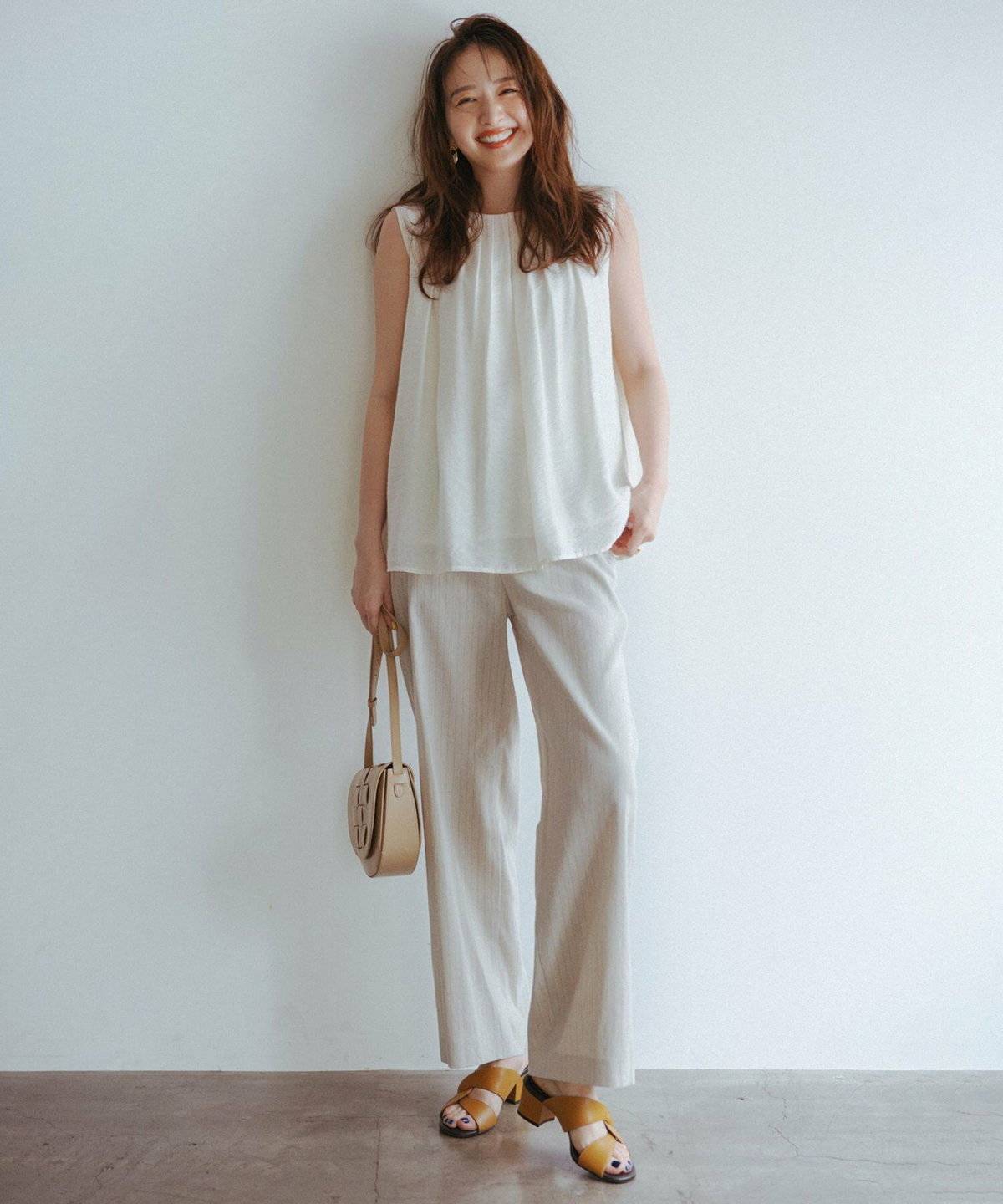 ベージュのブラウスにホワイトのトップスを合わせた女性