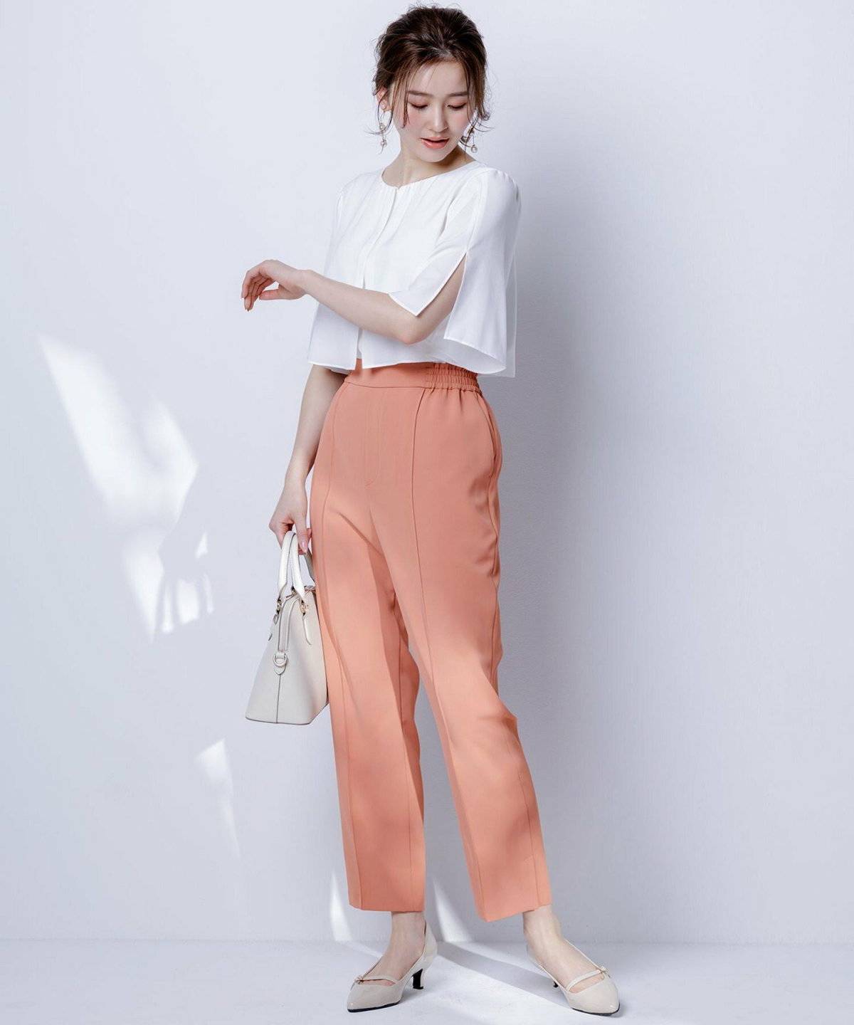 ホワイトのブラウスにパンツを合わせた女性